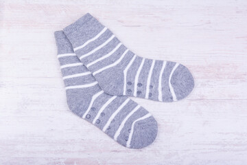 Pair of gray woolen socks on white wooden background