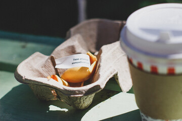 fortune cookie in hand and a cardboard cup of coffee