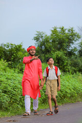 Young indian farmer telling some information to his child in green field