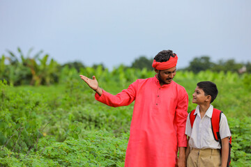 Young indian farmer telling some information to his child in green field