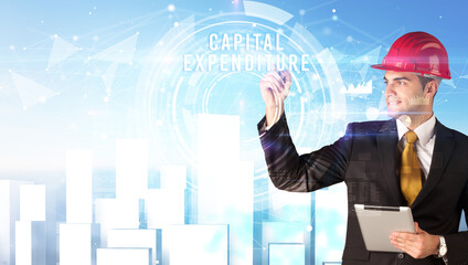 Handsome businessman with helmet drawing CAPITAL EXPENDITURE inscription, contruction business concept