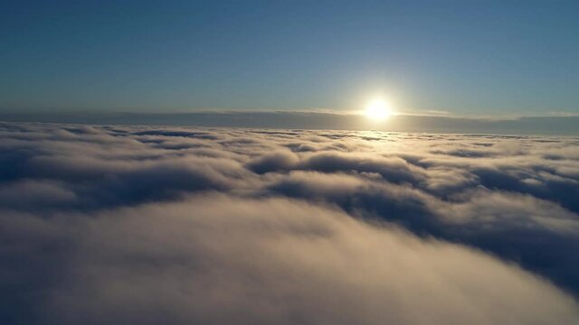 Aerial shot. Drone flying above the clouds during sunrise.