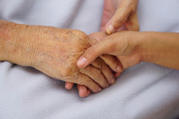Fototapeta premium Touching or holding hands asian senior or elderly old woman on a blue cloth with love, care, encourage and empathy.
