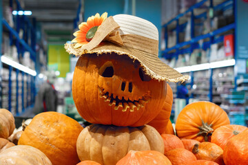 Pumpkin head in a straw hat on the counter in a store among other pumpkins. Halloween decoration.