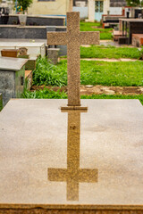 Cruz em túmulo com seu reflexo na base. Fotografia feita dentro do Cemitério Santana na cidade de Goiânia. 