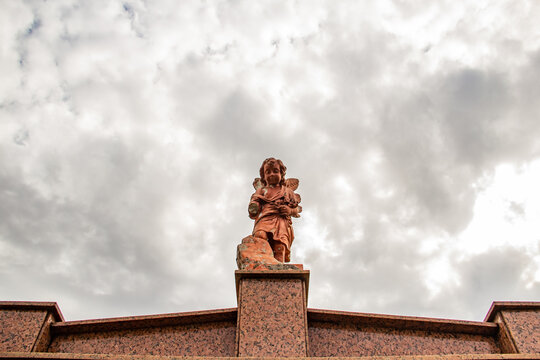 Imagem de anjo no topo de mausoléu em cemitério. Fotografia feita dentro do Cemitério Santana na cidade de Goiânia. 