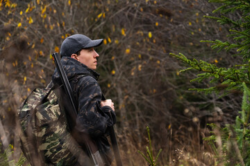 Obraz premium Hunter with a gun and a backpack in the forest 