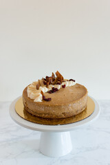Gourmet Pumpkin Cheesecake With White Cake Stand On White Marble Table