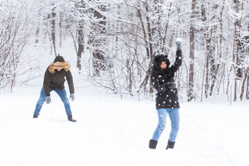 Fototapeta na wymiar Fun, season and leisure concept - love couple plays winter wood on snow