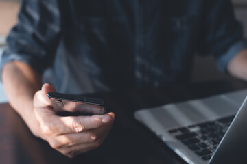 Man using mobile phone and surfing internet on laptop computer working in office