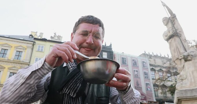 Man Jew eats soup from a plate on the street