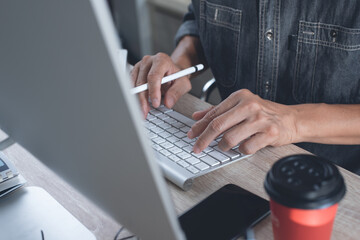 Close up of man working on desktop computer pc on office table and surfing the internet