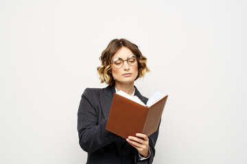 Woman at work with book in hand light background classic suit glasses head