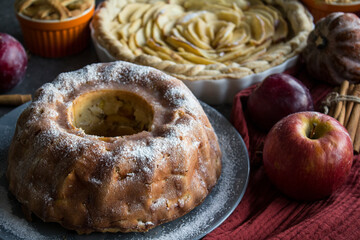 Apple pies of different types on a table with fresh fruits, cinnamon sticks and pumpkins. Autumn  menu ideas. Homemade dessert close up photo. 
