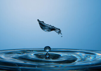 Water drop falling down. Abstract blue background.