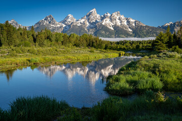 Fototapeta na wymiar Schwabachers Landing in the early morning in Grand Teton National Park, with mountain reflections on the water creek