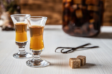 Likör aus Rhabarber, Vanille, Kandiszucker und Schnaps auf weißem Tisch mit braunem Hintergrund