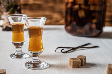 Likör aus Rhabarber, Vanille, Kandiszucker und Schnaps auf weißem Tisch mit braunem Hintergrund