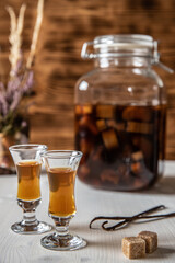 Likör aus Rhabarber, Vanille, Kandiszucker und Schnaps auf weißem Tisch mit braunem Hintergrund