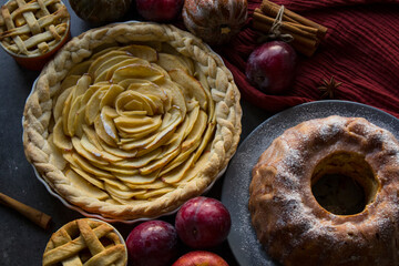 Apple pies of different types on a table with fresh fruits, cinnamon sticks and pumpkins. Autumn  menu ideas. Homemade dessert close up photo. 
