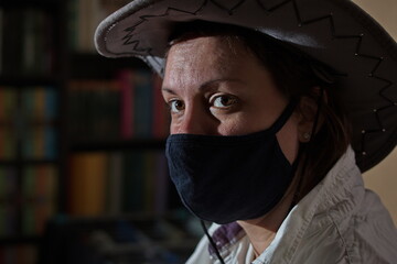 Portrait of a girl in a medical mask and a cowboy hat.