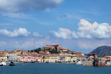 Fototapeta na wymiar Borgo e ingresso del porto di Portoferraio con imbarcazioni cielo e nuvole