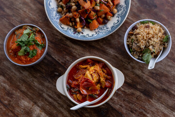 
full table healthy Indian, Asian and Mediterranean dishes with white beans, lentils, sweet potatoes, rice and vegetables