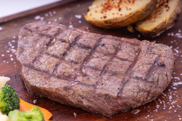 Meat grilled ribai with vegetables. Ribai steak on wooden board. Close up
