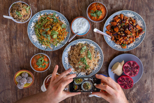 Cellphone taking picture of a table full of healthy and colorful asian and Mediterranean food