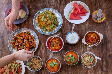 table full of healthy and colorful  food with detail of hands touching asian and Mediterranean food