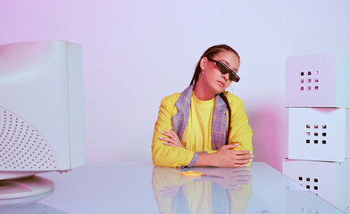 Modern young asian female office worker in sunglasses sitting at desk with old computer in neon...