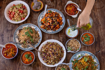 table full of healthy and colorful  food with detail of hands touching asian and Mediterranean food