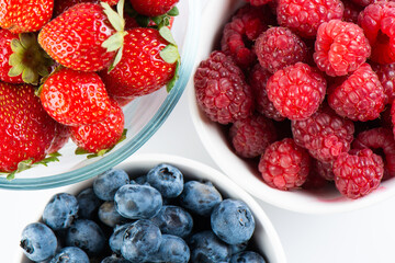 Fresh berries raspberries, strawberries and blueberries in bowls isolated on white background, top view