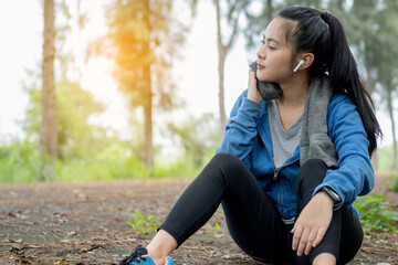 Tired young Asian runner woman is wiping her sweat after run in the morning.