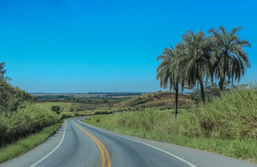 Fototapeta na wymiar Brazilian road with landscape of blue sky, mountains and green trees