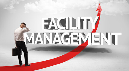 Rear view of a businessman standing in front of FACILITY MANAGEMENT inscription, successful business concept