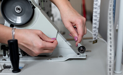 female hands adjust sewing machine for sewing