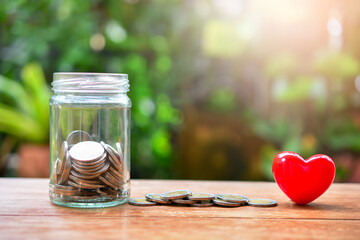 glass jar with money coins set with heart model for concept donation and philanthropy - obrazy, fototapety, plakaty
