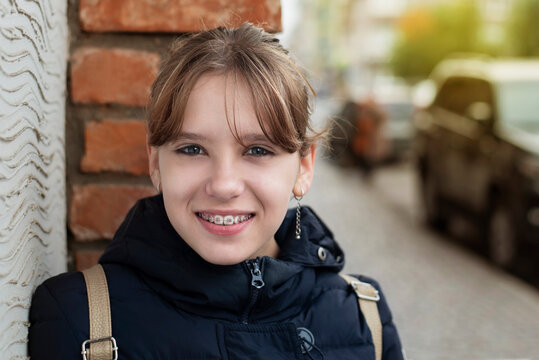 Pretty teen girl smiles nicely and rests in the city, she has been walking for a long time and a little tired, the girl has braces on her teeth