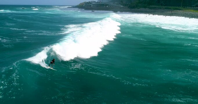 Aerial view of Surfer on blue-green waves, drone shots. Surf waves on the north coast of Madeira. Cinema 4K, slow motion. Surfing in Madeira, Portugal.