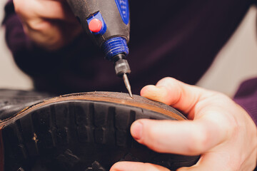A shoemaker cuts the sole of a Shoe with a shoemaker's automatic cutter.
