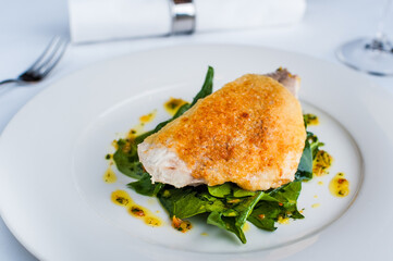 Dorado fish with spinach and curry sauce on a white plate