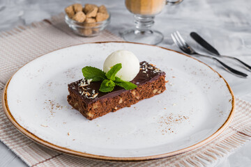 Brownie with a scoop of ice cream, decorated with a mint leaf with a cup of coffee