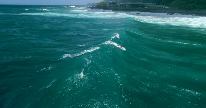 Aerial view of surf waves on the north coast of Madeira. Surfer on blue-green waves, drone shots. Cinema 4K, slow motion. Surfing in Madeira, Portugal.