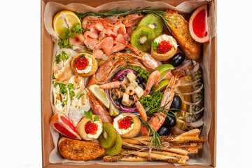 A box of food, cheese, breads, fish, shrimp. Food delivery for the company, romantic, office dinner at home. Beautiful composition of food in a box, convenient carrying, fresh products.