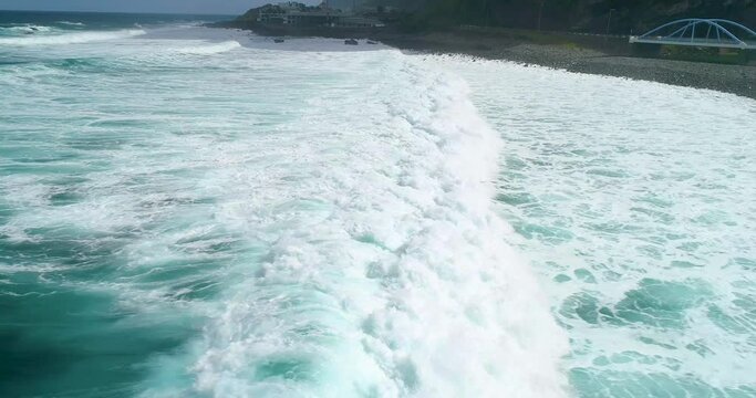 Aerial view of surf waves on the north coast of Madeira. Surfer on blue-green waves, drone shots. Cinema 4K, slow motion. Surfing in Madeira, Portugal.