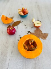 Wooden background with pumpkin, apple and pumpkin seeds. Vegan and healthy food in autumn.