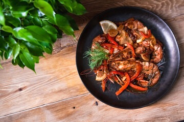 Delicious fried langoustines in sauce on a black plate, prepared in an Asian style. Fast and ready meal concept