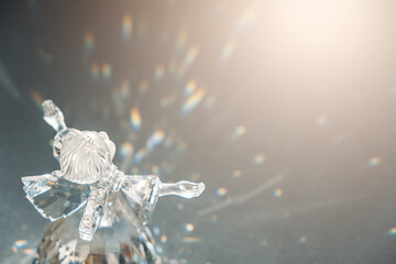 Crystal glass angel in the rays of the sun with reflecting, embossed sparkle. Faith, hope, mercy concept