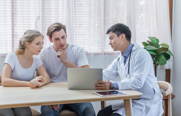 Caucasian couple patient husband and wife visit or meeting male doctor for pregnanct consultation at clinic or hospital. Lover meet medical advisor or physician for health treatment and medicare.